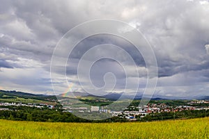 Landscape view with rainbow of the town of Valasske Mezirici during the rain in the hills on the horizon where the sun shines into
