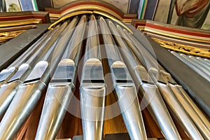 Landscape view of a rank of shiny steel pipes of a refurbished church organ