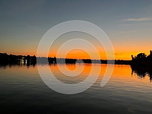 Landscape view reddish sunset with moon reflecting on lake