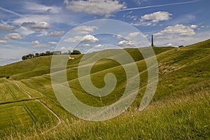 Landscape view of rolling hills, cereal fields and 19th century monuments on a hillside in Wiltshire, UK. photo