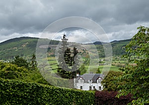 Landscape view of the rolling hills near Aberfeldy, in Highlands, Scotland UK. White painted Bolfracks House in foreground.