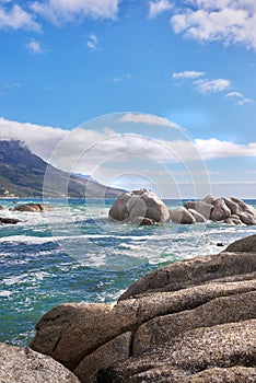 Landscape view of sea water, rocks and a blue sky with copy space in Camps Bay Beach, Cape Town, South Africa. Calm