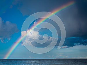 Landscape view on sky with rainbow at sea.