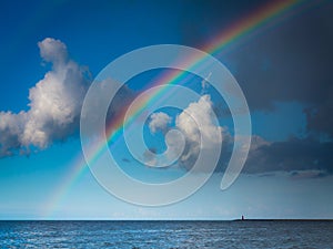 Landscape view on sky with rainbow at sea.