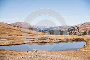 Landscape view of snow capped mountains and a pond at Independence Pass near Aspen, Colorado.
