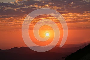 Landscape view of the sunrise from top to the mountain with orange color shade in the background with sun
