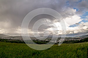 Landscape view of the town of Valasske Mezirici during the rain in the hills on the horizon where the sun shines into the photo