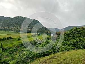 Landscape view of a Valley, Green fields with mountains and dark clouds in the sky