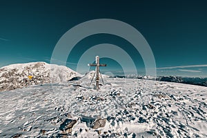 Landscape view with a wooden snowy cross in the Berchtesgaden Alps, clear sky in the background