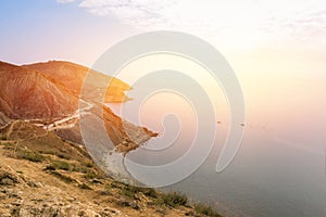 Landscape with views of the sea, mountains and a small resort town. Sunbeams and sunrise over the sea