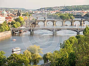 Landscape of the Vltava River with bridges over it surrounded by greenery and buildings in Prague
