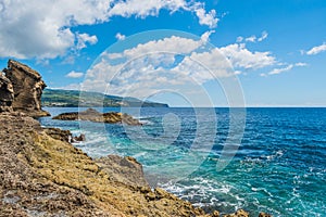 Landscape with volcanic rocks from the islet of Vila Franca with mountains of the island of SÃÂ£o Miguel in the background