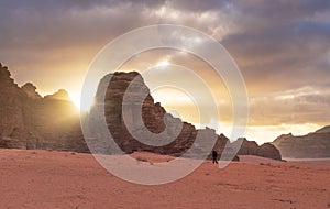 Landscape of Wadi Rum desert in sunrise with a man walking alone, and sunlight through stone mountain. Travelling and adventurous