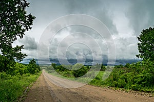 Landscape with a wide forest road and a sky with storm clouds