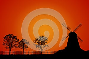 Landscape with windmill, trees and fence silhouette on orange sky background.