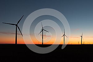 A landscape with windmills in a wind farm at sunset generating alternative and green energy source