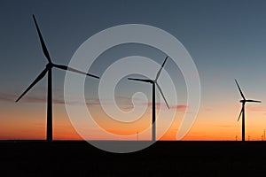 A landscape with windmills in a wind farm at sunset generating alternative and green energy source