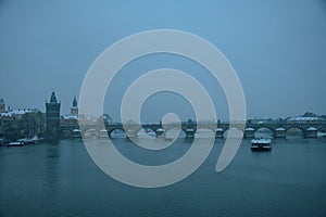 landscape in winter in Prague, Czech Republic with Vltava river, Karlov most and boat in evening