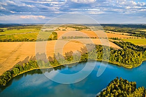 A landscape with yellow fields and a blue lake