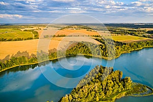 A landscape with yellow fields and a blue lake. Classic European farmlands