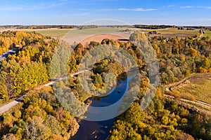 A landscape with a yellow and red forest and a winding river