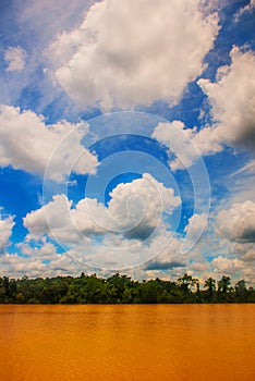 Landscape with yellow river and blue sky with clouds. Malaysia, Borneo