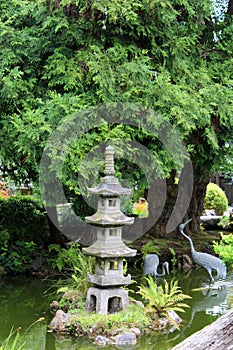 A landscaped Japanese garden with a Japanese stone lantern and bird statues in a pond in Californi
