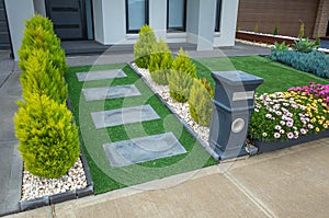 A landscaped small front yard with a paver walkway to the front porch and synthetic turf.