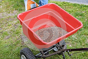 Landscapers gardener with sowing lawn grass seeds with a drop lawn spreader