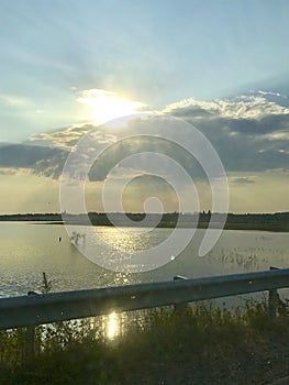 Landscapes of Transcarpathia. The setting sun breaks through the clouds. The sun`s rays are reflected in the water surface of the