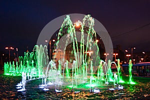 Landscaping - a beautiful fountain illuminated by luminous green lights against a dark blue night sky