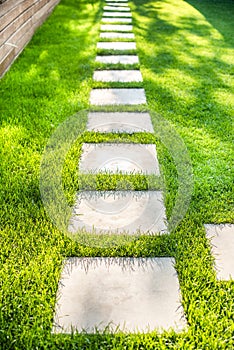 Landscaping of the garden with a path of individual palettes. stone squares on the lawn. summer, green grass, sun glare