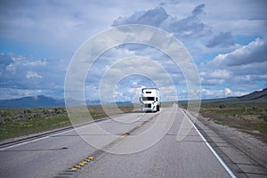 Landscaping with white semi-truck and long road in Nevada