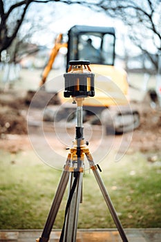 Landscaping works with excavator. Surveyor equipment optical level or theodolite at construction site