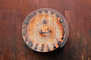 Landschaftspark Duisburg, Germany: Close up of isolated round rusty weathered metal hatch cover on corrugated brown steel wall