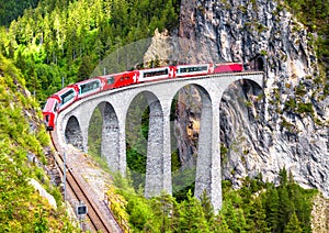 Landwasser Viaduct in Filisur, Switzerland. It is landmark of Swiss Alps. Bernina Express train on railroad bridge in mountains.