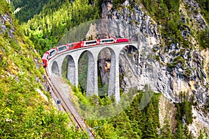 Landwasser Viaduct in summer, Filisur, Switzerland. It is landmark of Swiss Alps. Nice Alpine landscape. Red train of Bernina