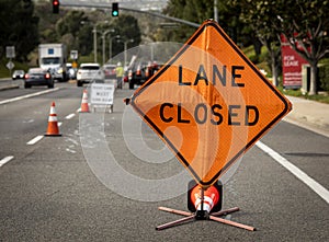 Lane Closed orange diamond shaped sign with work crew in distance