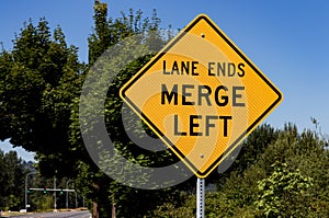 Lane ends merge left sign with trees