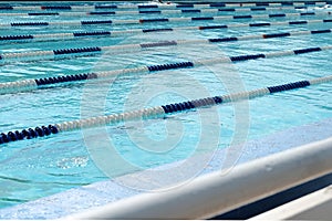 Lanes of swimming pool over light blue transparent water.