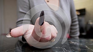 language of the body. close-up of a female hand with a black manicure beckons towards her with her index finger