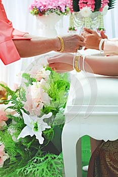 Lanna thread tightening or Thai style wedding tie ceremony , the bride`s hands are tied with white thread from elderly woman