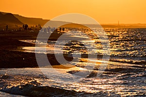 Beautiful sunset seashore landscape with people and mountains on background