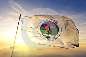 Lansing city capital of Michigan of United States flag textile cloth fabric waving on the top sunrise mist fog
