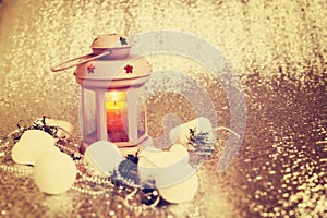 Lantern with burning candle surrounded by Christmas-tree decorations