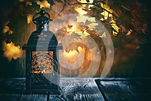 Lantern with candles on a background of autumn nature, yellow leaves in the sunlight. Retro and vintage sittle. Selective focus,