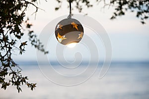 Lantern from the coconut tree with lamp on the background of sunset on the beach