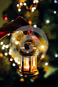 A lantern in a hand in darkness with a lit candle inside