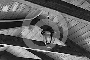 The lantern with iron fixtures to the wall and a glass canopy mounted on a wooden log house