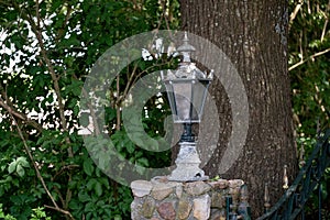 A lantern or lamp made of metal on a brick post. Old retro style